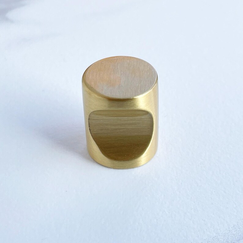 May include: A gold-toned cylindrical cabinet knob with a rounded top and a cutout on the front.