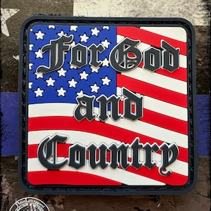 May include: A black and white patch with an American flag design. The patch has the words "For God and Country" in a gothic font.