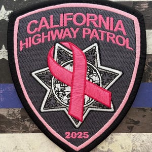 May include: A patch featuring the text "CALIFORNIA HIGHWAY PATROL" in pink, with a pink ribbon and a star emblem. The patch has a black border and the year "2025" at the bottom. The background is a distressed American flag.