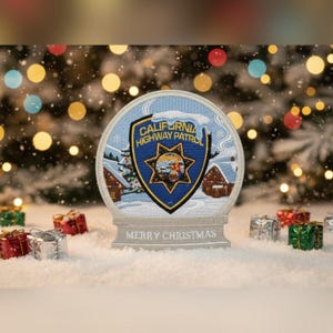 May include: A snow globe featuring the California Highway Patrol emblem. The globe has a winter scene with houses and snow. The base reads "MERRY CHRISTMAS". Small wrapped gifts are scattered around the base.