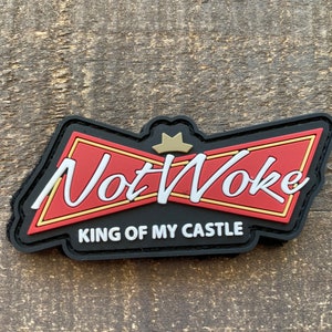 May include: Black and red patch with a white crown and the text "Not Woke" in white with a gold outline. The text "King of My Castle" is in white below the main text.