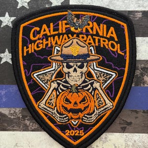 May include: A black and orange California Highway Patrol patch with a Halloween theme. The patch features a skeleton holding a jack-o'-lantern, with the text "CALIFORNIA HIGHWAY PATROL" and the year "2025". A bat is at the top.