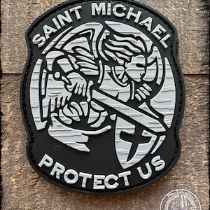 May include: Black and white patch with a stylized image of Saint Michael, an angel with a sword and shield, with the text "SAINT MICHAEL PROTECTUS" around the image.