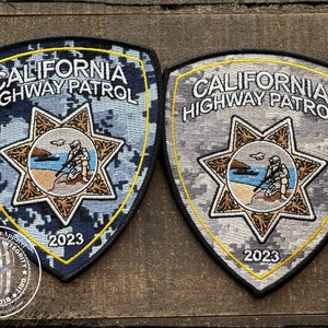 May include: Two embroidered patches with a blue and grey camouflage pattern. The patches are shaped like a shield and feature the text "CALIFORNIA HIGHWAY PATROL" and a star with a California state outline and a law enforcement officer. The year 2023 is embroidered on the bottom of each patch.