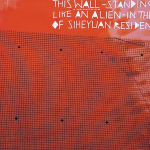 May include: A red wall with a black grid pattern and white text that reads "SOME MONTHS LATER STROLL IN THE HUTONG LAMA TEMPEL IN BEIJ A SUNNY WEDNESDAY THIS WALL-STANDING LIKE AN ALIEN-IN THE OF SIHEYUAN RESIDEN 京,雍和宁区:儿".