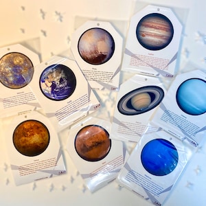 May include: Set of nine colorful planet cards with images and descriptions of each planet in our solar system. The cards are printed on white cardstock and feature a simple, modern design.