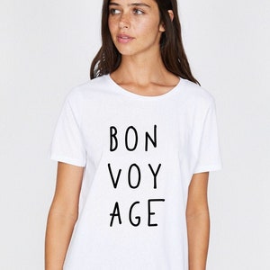 Op de afbeelding: Wit T-shirt met zwarte tekst die "BON VOY AGE" zegt.
