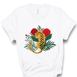 May include: White t-shirt with a graphic of a yellow leopard with black spots surrounded by green leaves and red roses.