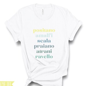 Puede incluir: Camiseta blanca con el texto "positano amalfi scala praiano atranı ravello" impreso en un degradado de amarillo, azul y verde.