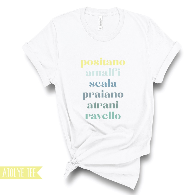 Puede incluir: Camiseta blanca con el texto "positano amalfi scala praiano atranı ravello" impreso en un degradado de amarillo, azul y verde.