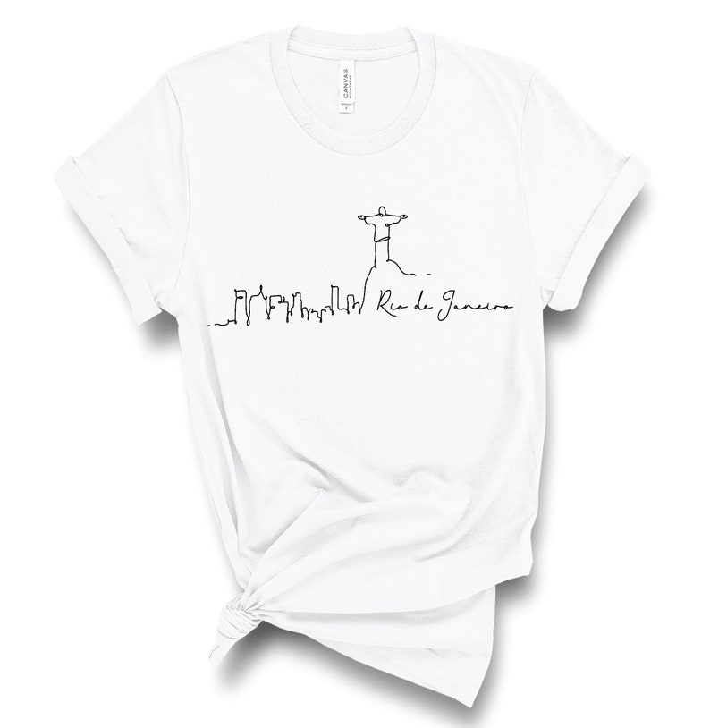 May include: White t-shirt with a black line drawing of the Christ the Redeemer statue in Rio de Janeiro, Brazil. The drawing also includes a skyline of the city and the text "Rio de Janeiro".