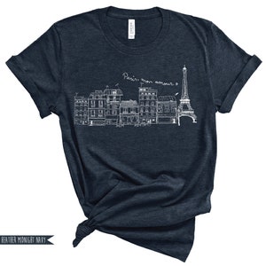 May include: A dark blue t-shirt with a white graphic of the Eiffel Tower and Parisian buildings. The text "Paris, mon amour" is written above the graphic.