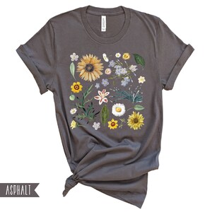 May include: A gray t-shirt with a floral print featuring sunflowers, daisies, and other flowers in shades of yellow, white, and blue.