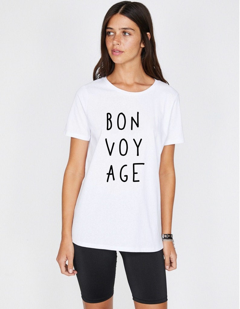 Op de afbeelding: Wit T-shirt met zwarte tekst die "BON VOY AGE" zegt.