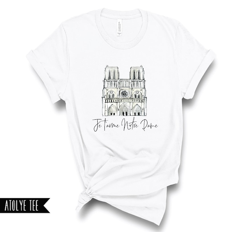 May include: White t-shirt with a black and white illustration of the Notre Dame Cathedral and the text "Je t'aime Notre Dame".