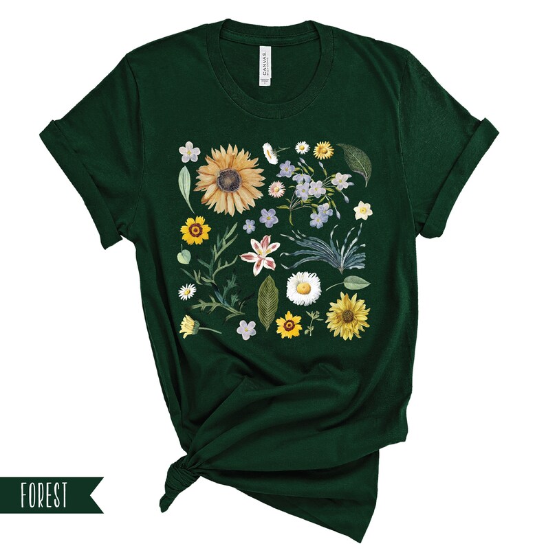May include: A dark green t-shirt with a floral print featuring sunflowers, daisies, and other wildflowers. The print is centered on the shirt and covers most of the front.