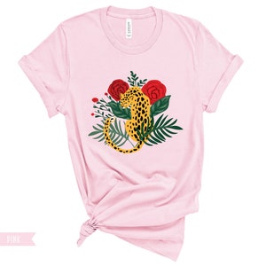 May include: A pink t-shirt with a graphic of a leopard curled up in a bed of red roses and green leaves.