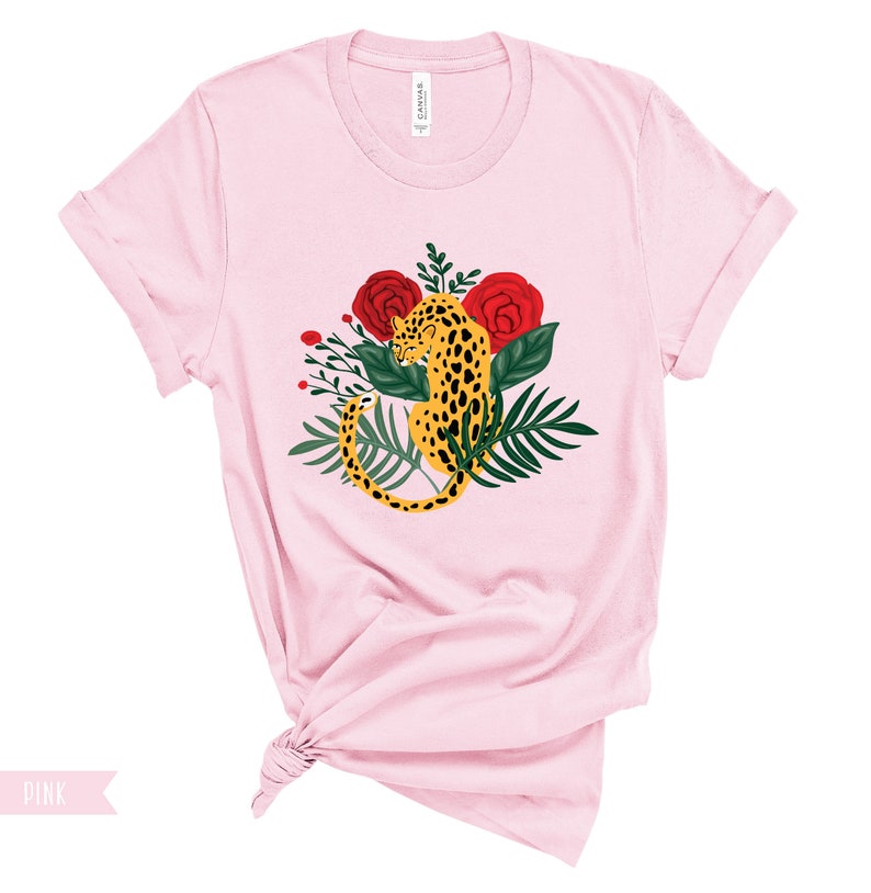 May include: A pink t-shirt with a graphic of a leopard curled up in a bed of red roses and green leaves.