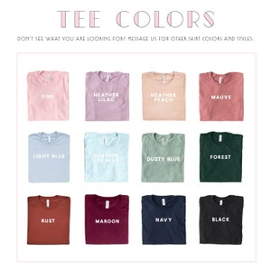 May include: A grid of 12 folded t-shirts in various colors, including pink, light blue, rust, maroon, navy, and black. Each shirt has a different color and a text label indicating the color name.