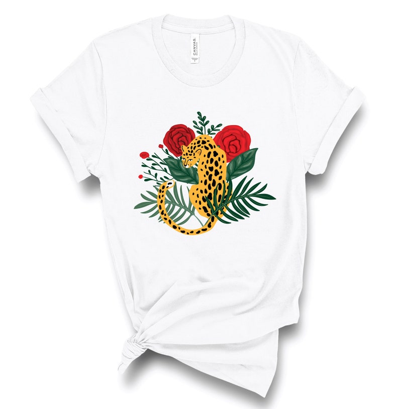 May include: White t-shirt with a graphic of a yellow leopard with black spots surrounded by green leaves and red roses.