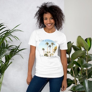 May include: White t-shirt featuring a graphic of palm trees and the text "Los Angeles California" in a blue circle.