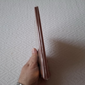 Op de afbeelding: Een bruin hardback boek met een licht gebogen rug.
