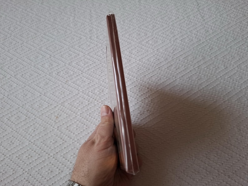 Op de afbeelding: Een bruin hardback boek met een licht gebogen rug.