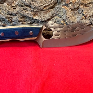 May include: A blue and wood handled knife with a textured, silver blade. The blade has a hole in it and a rounded tip.