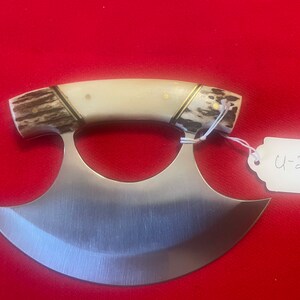 May include: A silver, curved knife with a handle made of bone and ivory. The handle has a gold inlay. The knife has a tag attached to it that says "U-278".