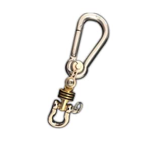 May include: A silver swivel snap hook with a brass pulley and a silver D-ring. The snap hook has a small metal tag with the number "316" on it.