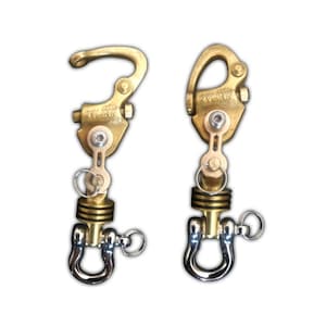May include: Two gold-colored metal boat cleat hooks with a swiveling shackle on the bottom. The cleat hooks have a black and gold striped cylinder in the middle and the text "KYLINK" is engraved on the side.
