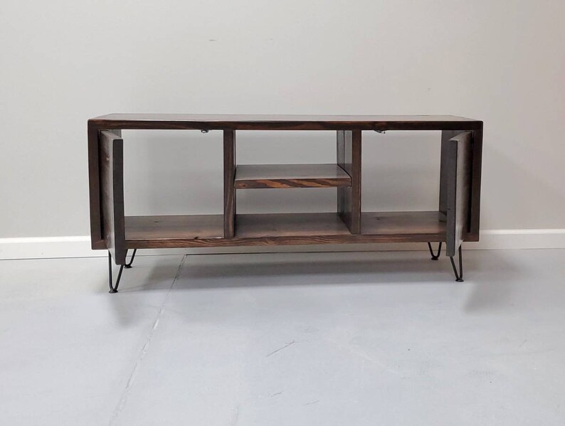 May include: A dark brown wooden media console with two open shelves and two doors. The console has hairpin legs and is sitting on a white floor.