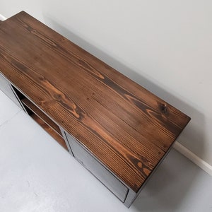 May include: A dark brown wooden media console with two doors and shelves. The console has a distressed wood finish and a rectangular shape.
