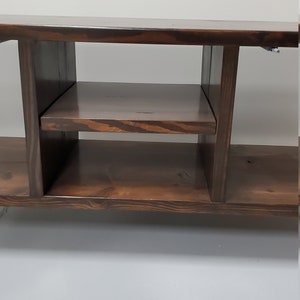 May include: A dark brown wooden entertainment center with two shelves and open compartments. The unit has a simple, modern design.