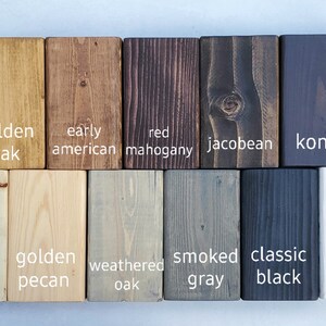 May include: A collection of wooden blocks showcasing various wood stain colors. Colors include golden oak, early American, red mahogany, and jacobean. Additional colors are kona, golden pecan, weathered oak, smoked gray, classic black, and white.