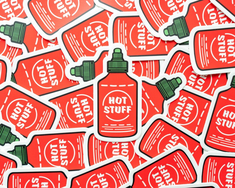 May include: A close-up of several red and white stickers with the text "Hot Stuff" and a cartoon image of a hot sauce bottle. The stickers are arranged in a random pattern.