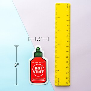 May include: A red and green hot sauce bottle sticker with the text "HOT STUFF" on a white background. The sticker is 3 inches tall and 1.5 inches wide.