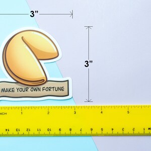 May include: A white sticker with a yellow fortune cookie illustration and the text "Make your own fortune". The sticker is 3 inches wide and 3 inches tall.