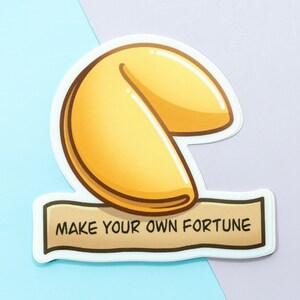May include: A white sticker with a cartoon illustration of a fortune cookie and the text "Make your own fortune".