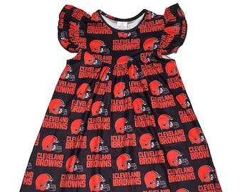 May include: A black and orange sleeveless dress with a ruffled neckline and short sleeves. The dress is covered in a repeating pattern of the Cleveland Browns logo, which includes the team name and a football helmet.