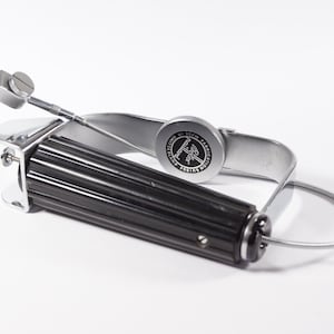 Könnte beinhalten: Ein Vintage-Instrument aus Metall und schwarzem Kunststoff mit geriffeltem Griff und einem runden Einstellrad mit der Aufschrift "Boker Maillard Fabrication Suisse". Das Gerät verfügt über eine dünne, flexible Drahtschlaufe und eine Stellschraube.