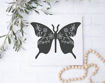 May include: Black and white silhouette of a butterfly with floral details on a white background.