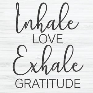 May include: Black and white typography on a white wood background. The text reads "Inhale Love Exhale Gratitude".