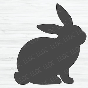 Może przedstawiać: Sylwetka królika siedzącego na białym tle z imitacją drewna.