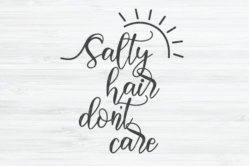 May include: Black and white calligraphy text on a white wood background. The text reads "Salty hair don't care" with a sun graphic above the word "Salty".