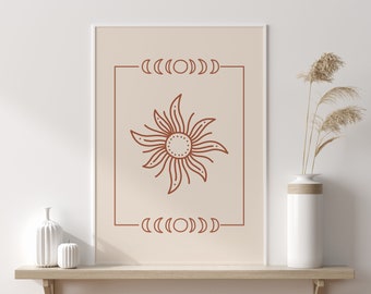 May include: A minimalist wall art print featuring a brown line drawing of a sun with a circle in the centre and crescent moons on either side of the sun. The print is framed in a white frame and is hanging on a white wall.