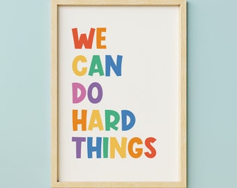 May include: A framed print with the text "WE CAN DO HARD THINGS" in rainbow colors. The text is in a playful, bold font.
