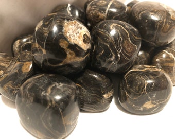 May include: A collection of tumbled stones in black and brown with swirling patterns. The stones are smooth and polished, and they have a natural, organic look.