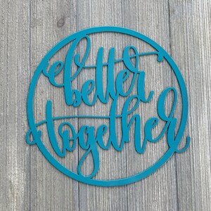 May include: Teal blue circular wooden sign with the words "Better Together" written in a decorative script font.