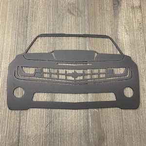 May include: Black metal silhouette of a Chevrolet Camaro car front end. The car has a black grille and headlights.